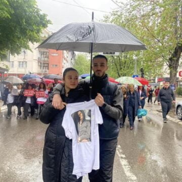 E dhimbshme: Vajza e Gjyljeta Ukellës mban në dorë bluzën me foton e nënës së saj gjatë marshimit sot në Pejë